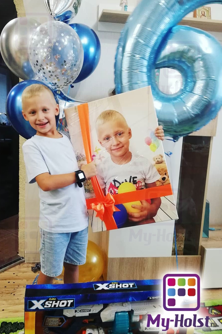 Мальчик держит картину со своим фото в подарочной упаковке